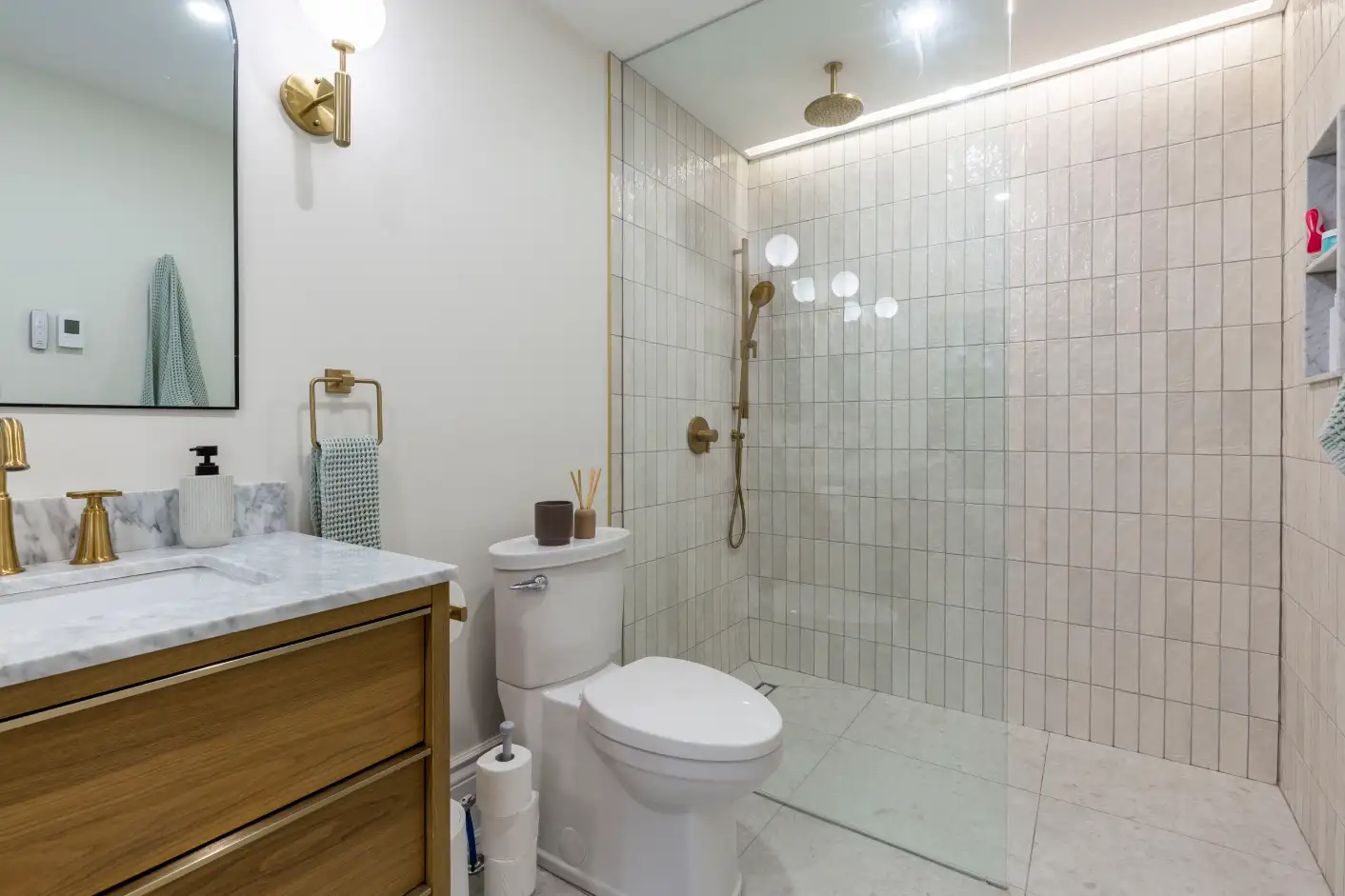 Bathroom with glass shower, wood vanity and gold fixtures