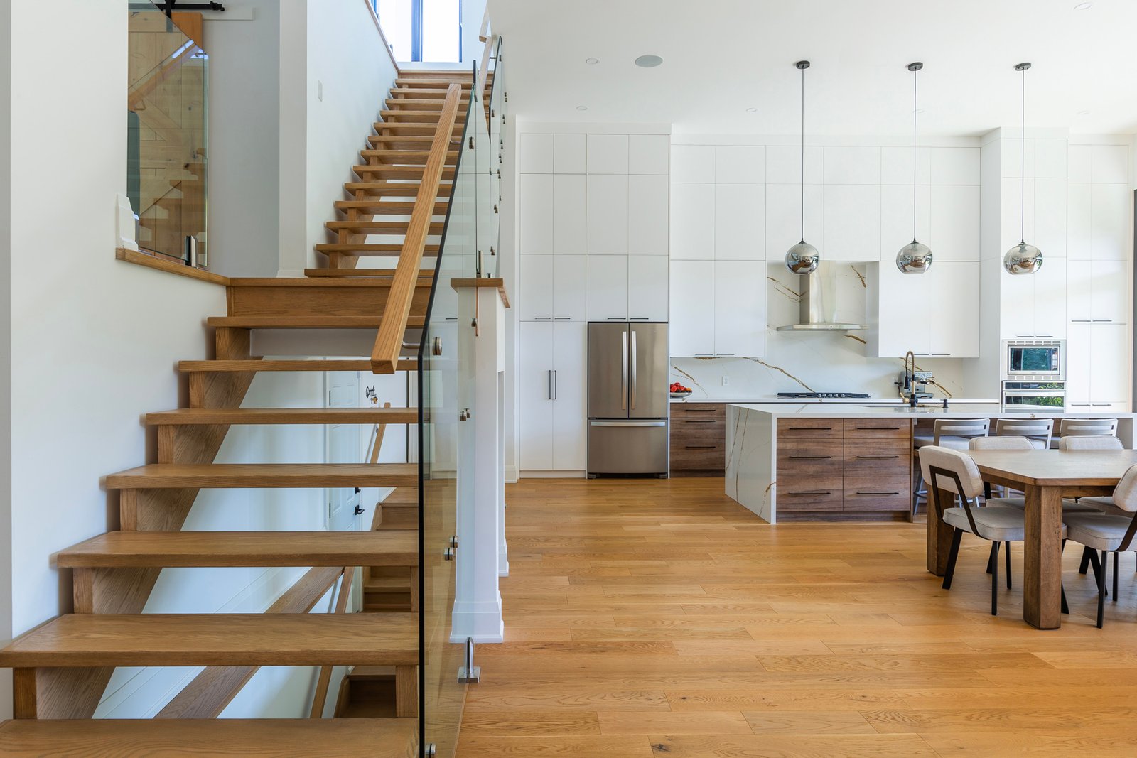 Wood stairs with glass railing beside the open kitchen