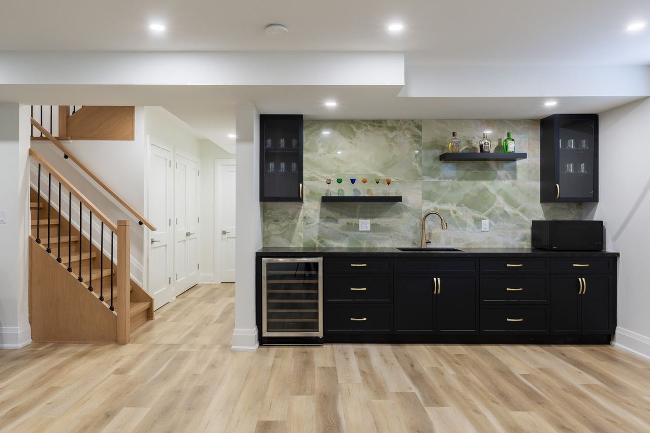 Basement wet bar with black cabinetry and green onyx backsplash