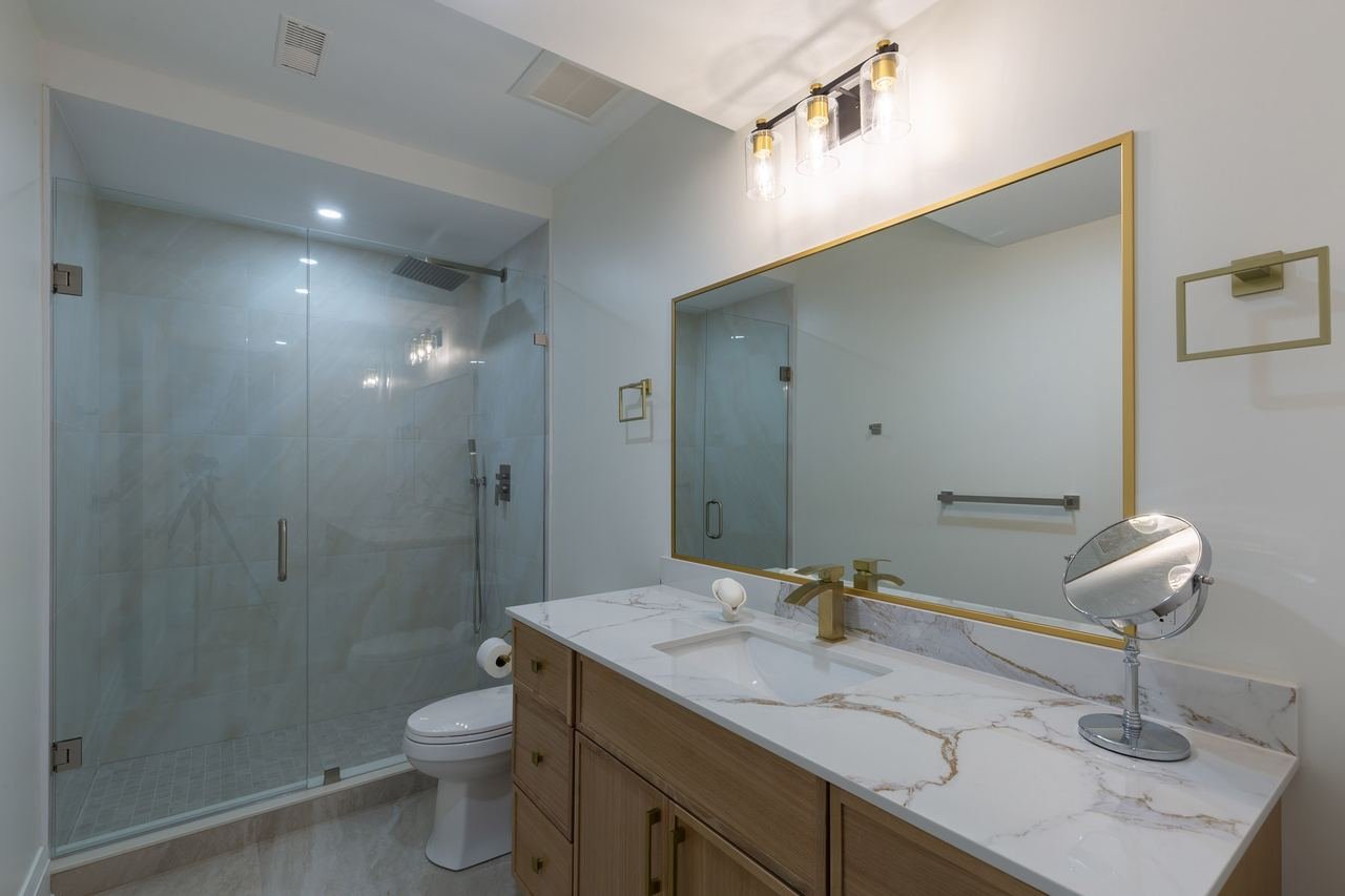 Bathroom with glass shower, wood vanity and gold accents