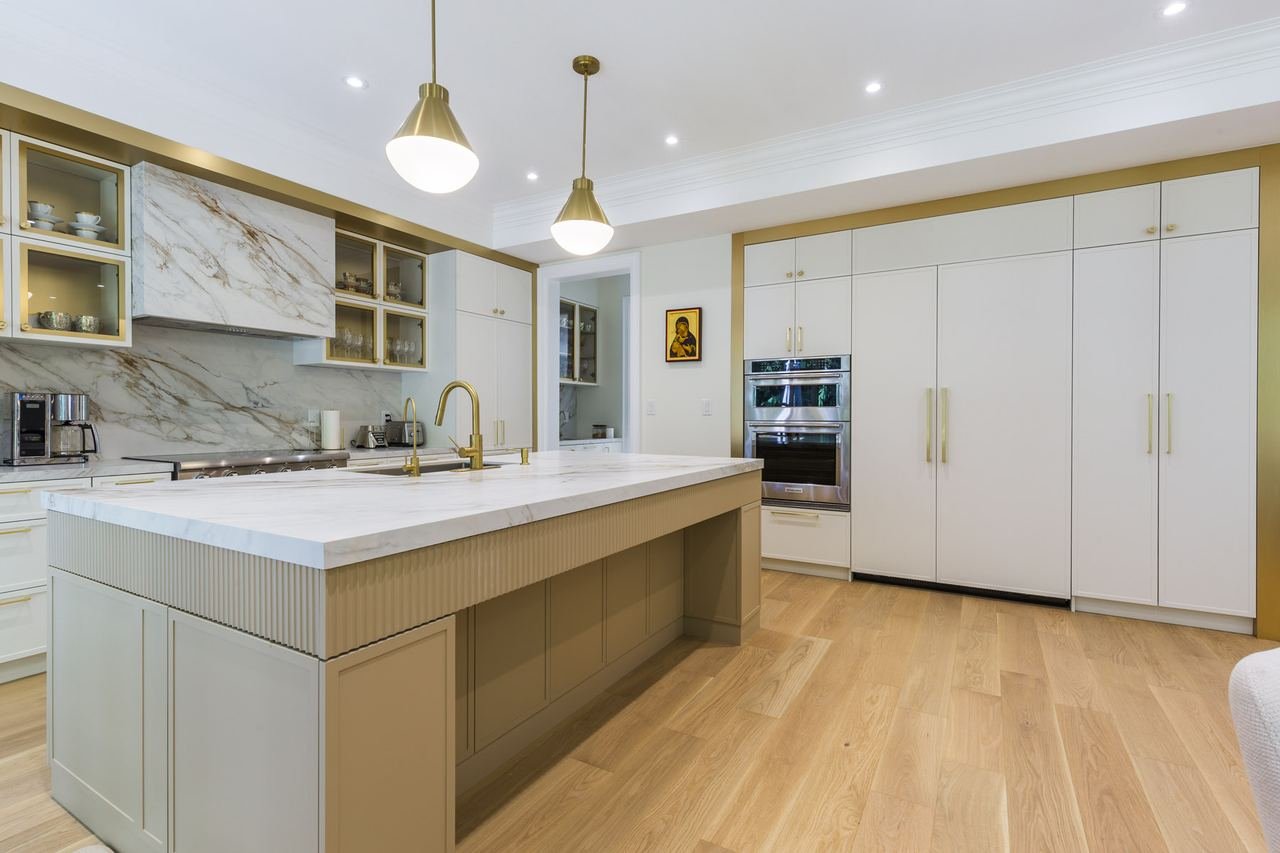 Custom kitchen with white cabinetry, marble backsplash and large island