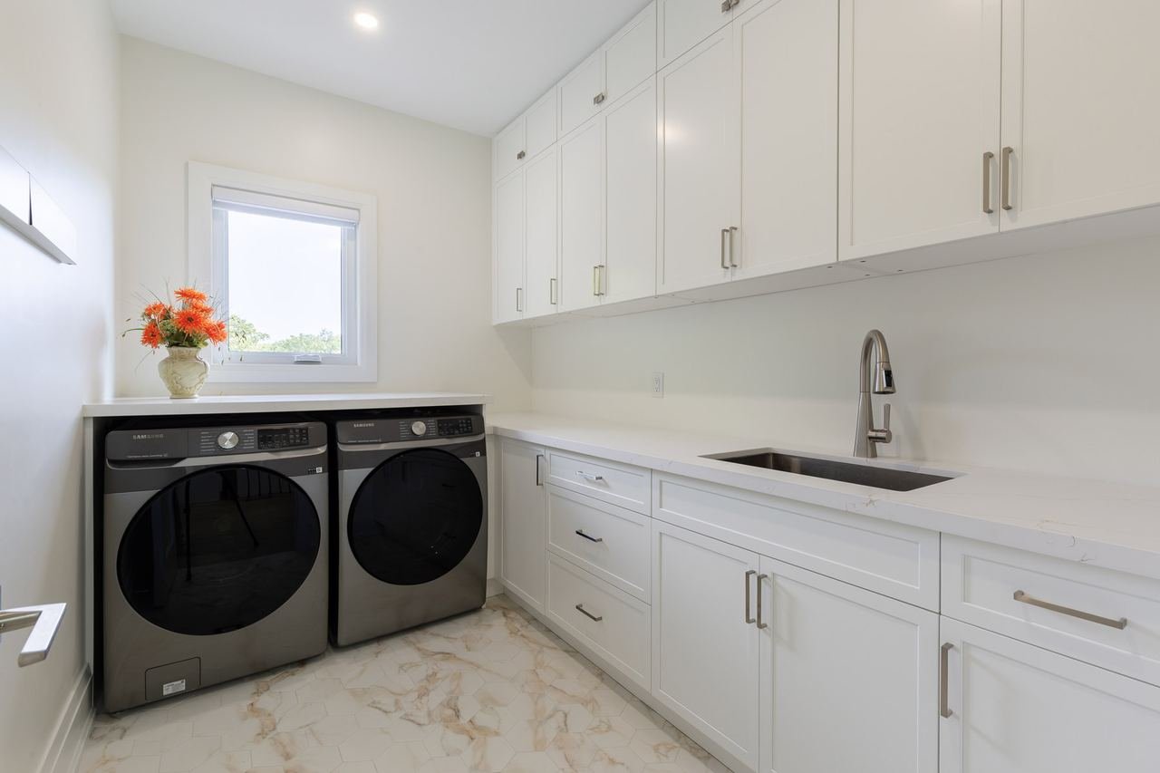 Laundry room with white cabinetry and black appliances