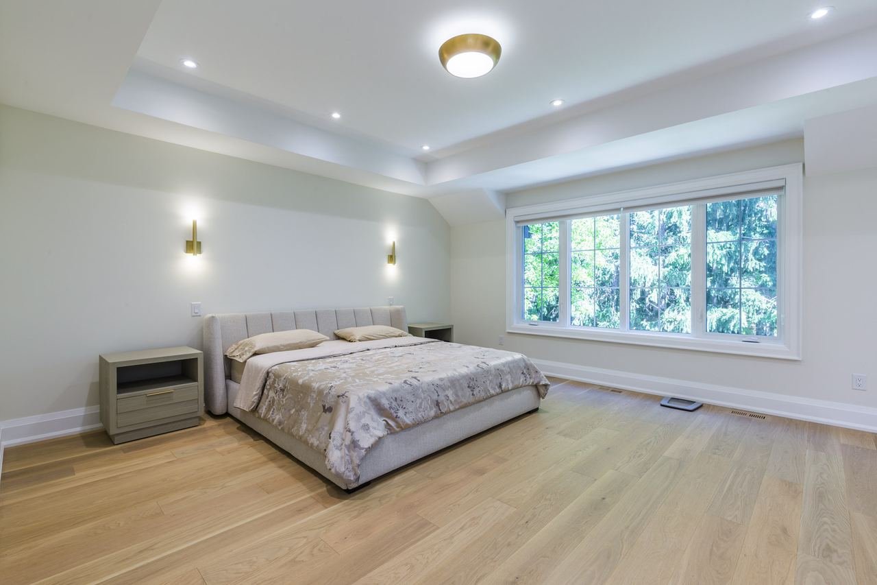 Primary bedroom with tray ceiling and wall sconces