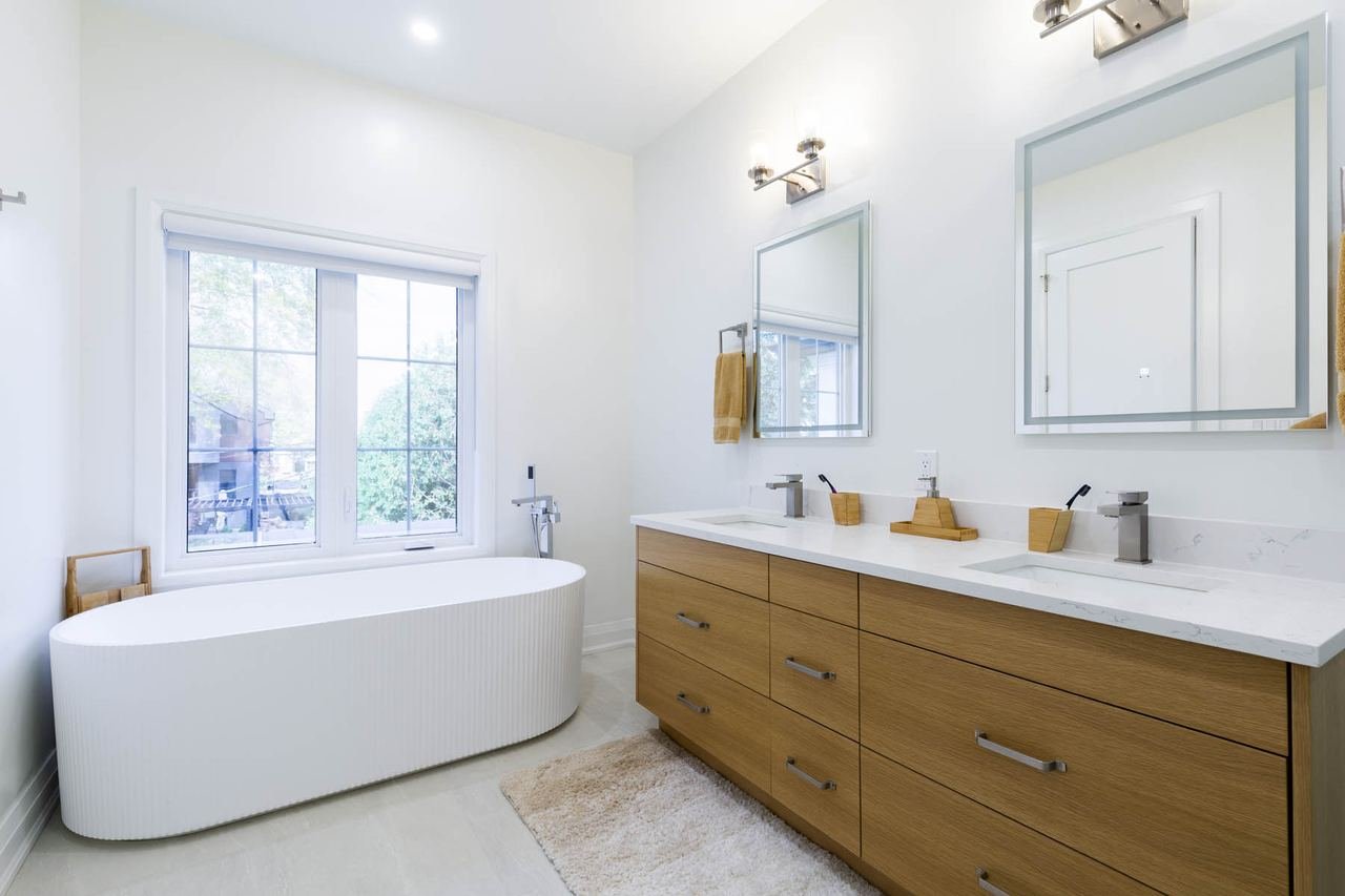 Primary ensuite with freestanding tub and double wood vanity