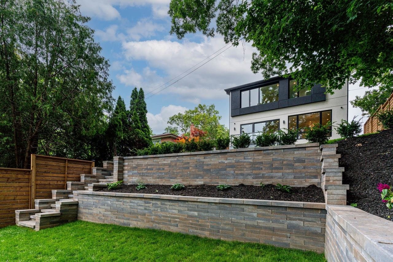 Rear stone retaining wall and landscaping with modern home view