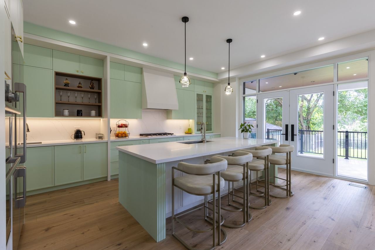 Sage green kitchen with island seating and walkout to covered patio