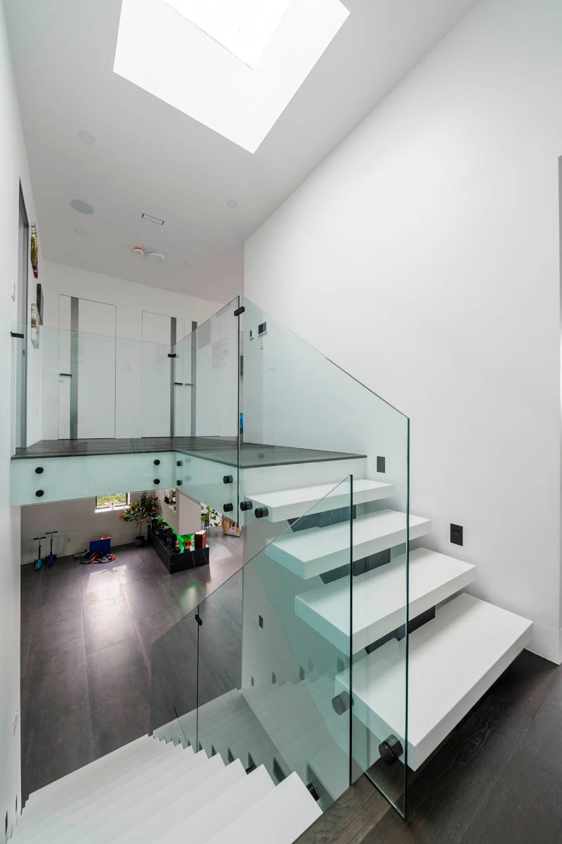 Staircase with glass railing and skylight above