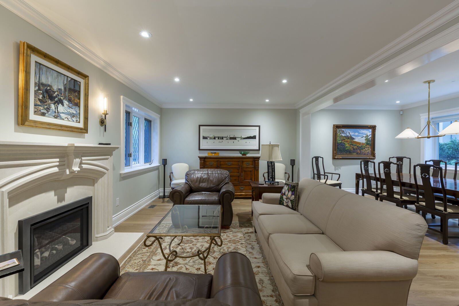 Renovated living room with limestone fireplace mantel and open flow to dining room