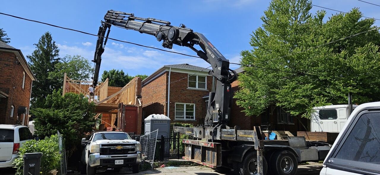 Boom truck lifting framing lumber to the second-storey addition on Balliol St