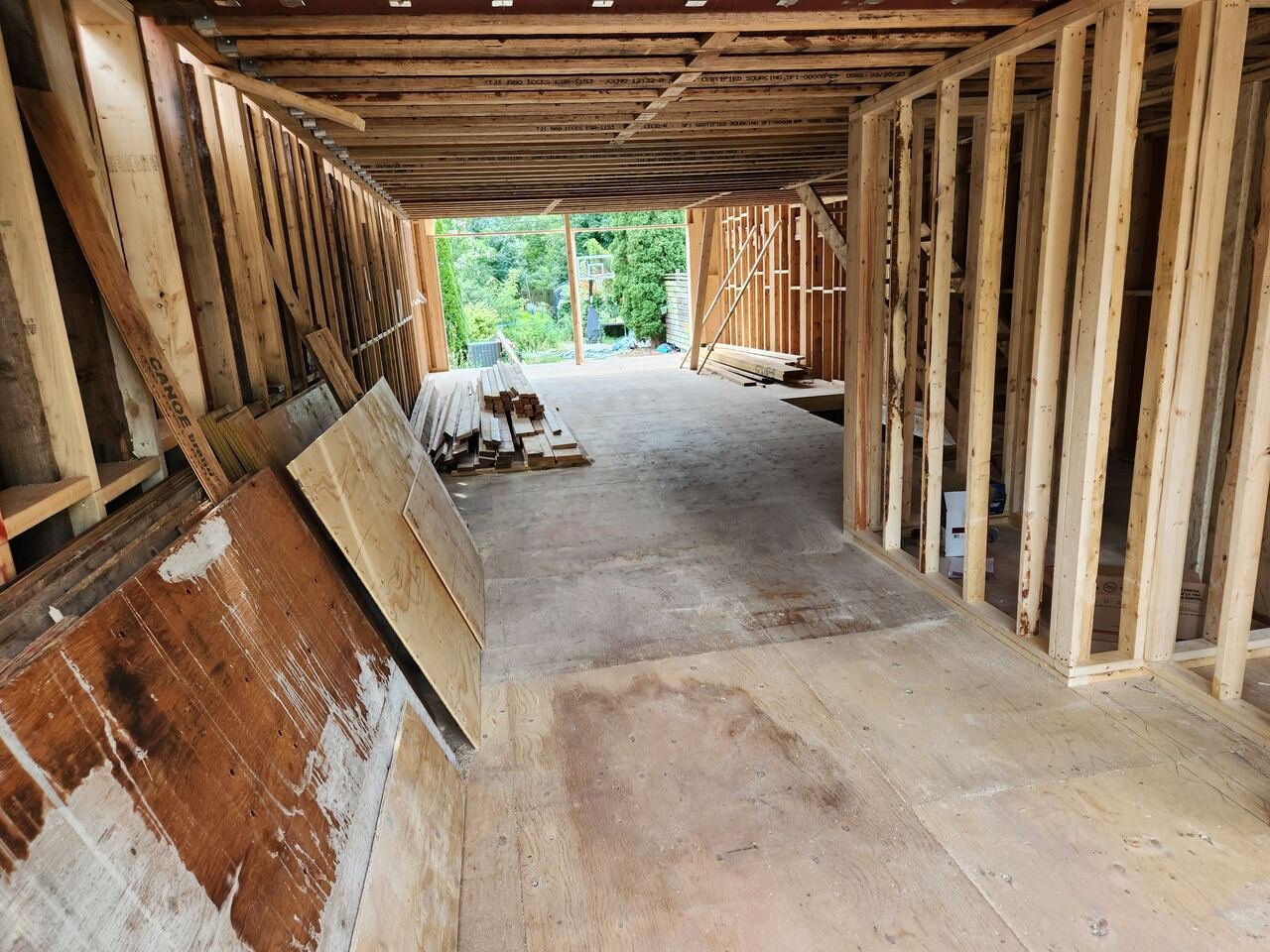 Gutted main floor stripped to the studs with new subfloor and framing lumber staged for install