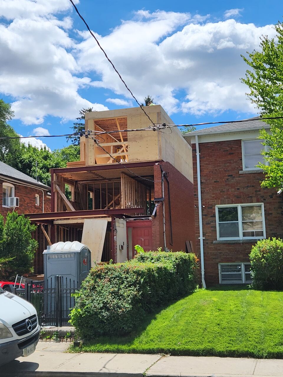 Original brick house supported on steel beams while the new plywood-sheathed second storey is framed above