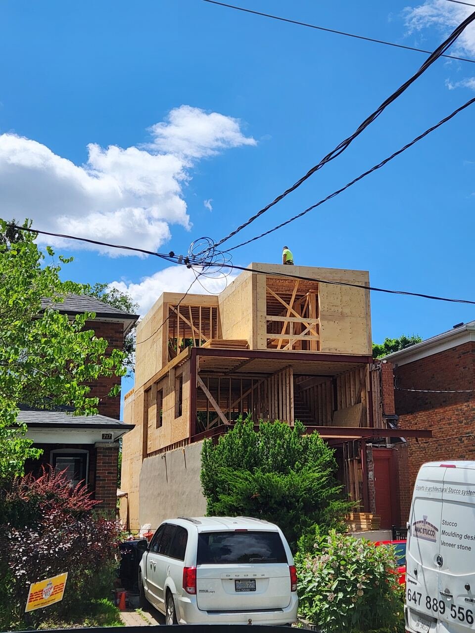 Plywood-sheathed second-storey box in place above the existing structure with a crew member on the roof