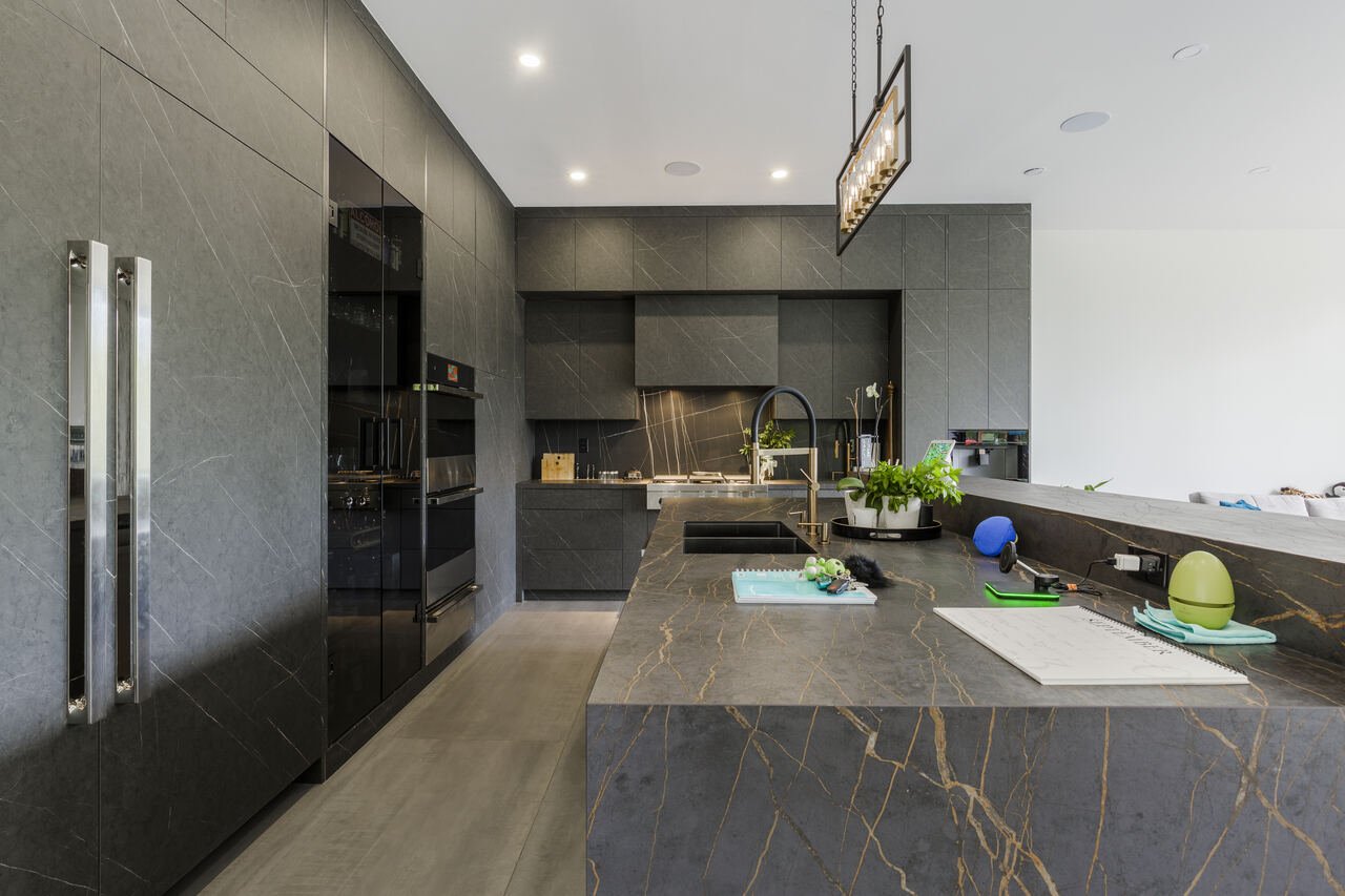 Kitchen with gold-veined stone island, integrated appliances and pendant lighting