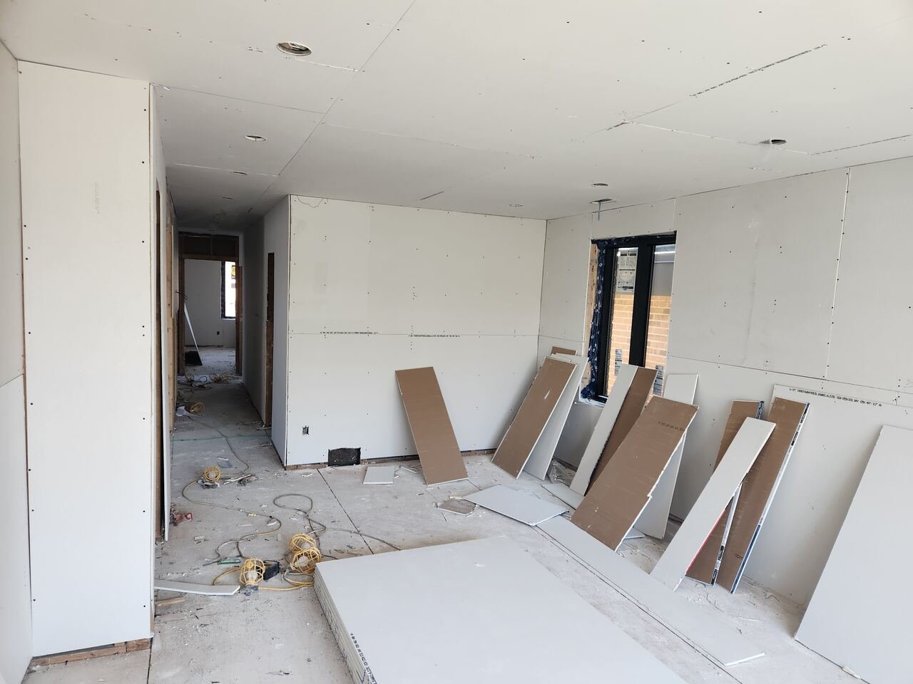 Living room at drywall stage with boards stacked ready for install