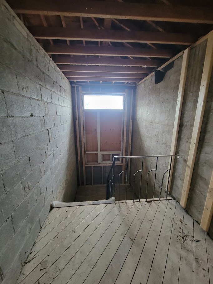 View down the rebuilt stairwell with new framing and temporary railing