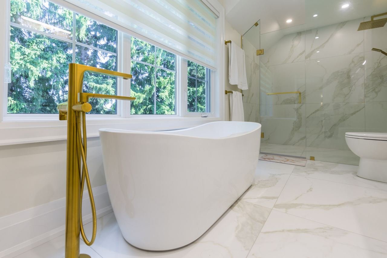 Primary ensuite with freestanding tub, gold floor faucet and marble tile
