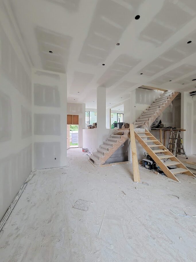 Main floor interior at drywall stage with staircase framing