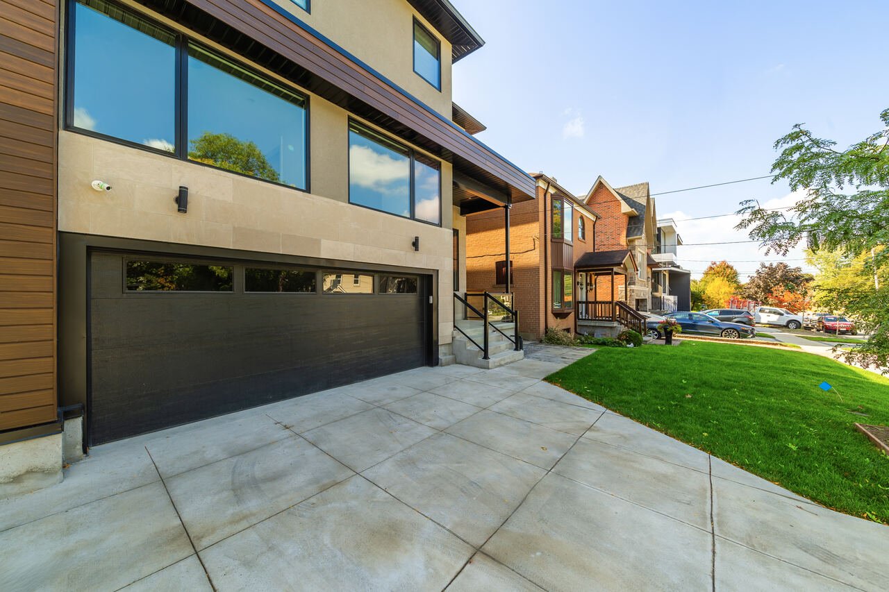 Front exterior of Lansing custom home with stone facade, black garage door and concrete driveway