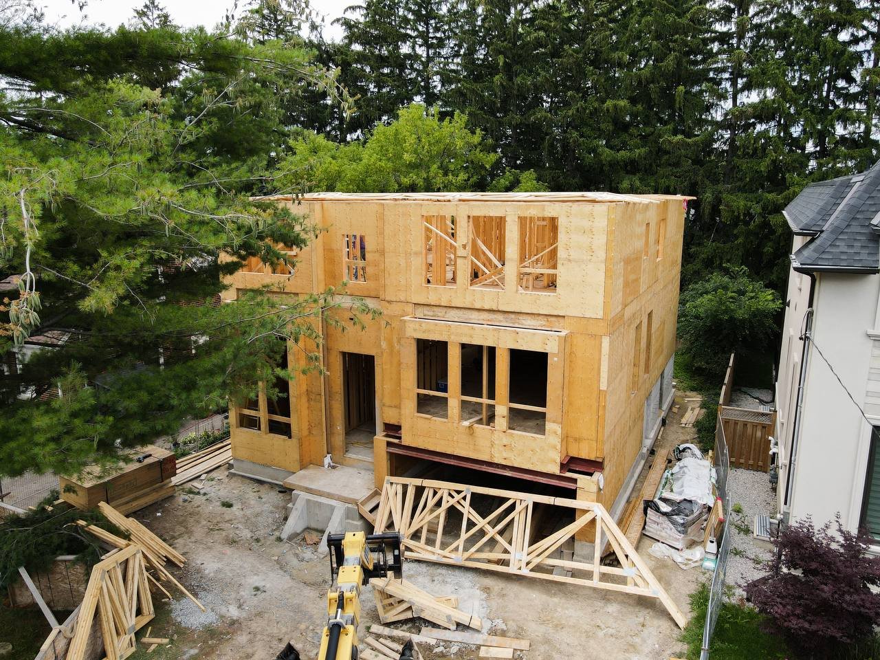 Aerial view of the framed custom home with roof trusses staged in the driveway