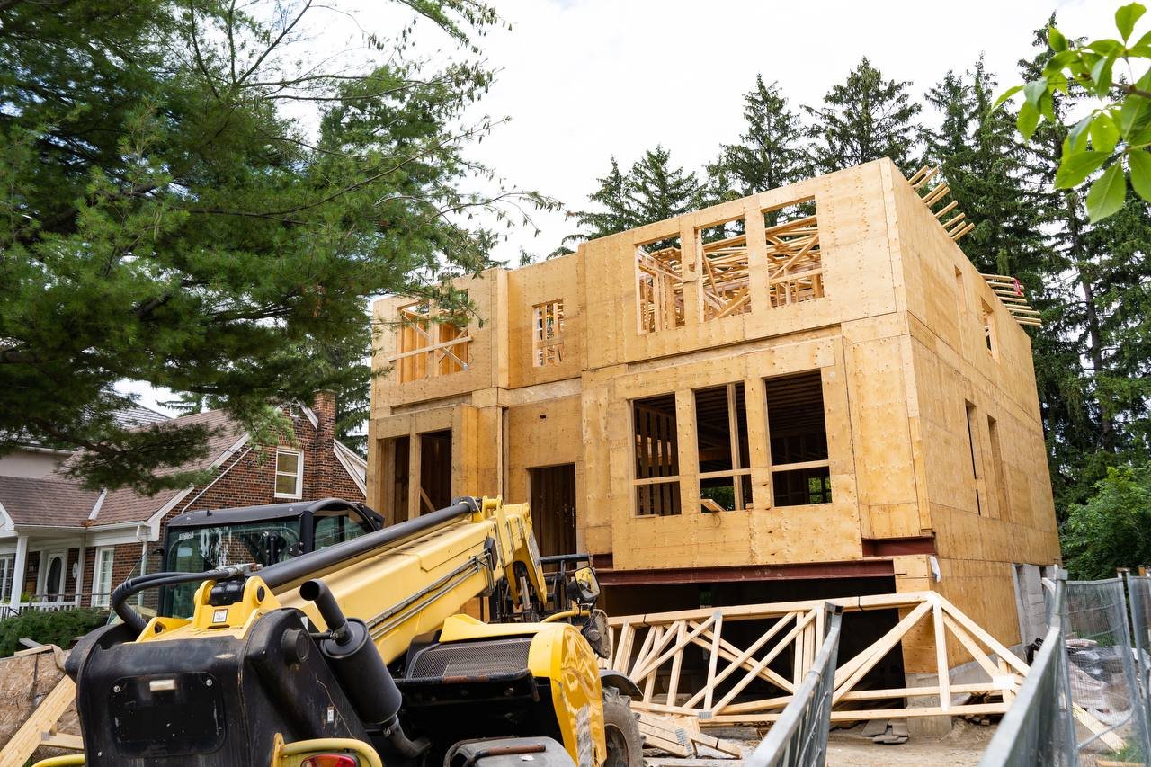 Front elevation framed and sheathed with telehandler on site and roof trusses staged