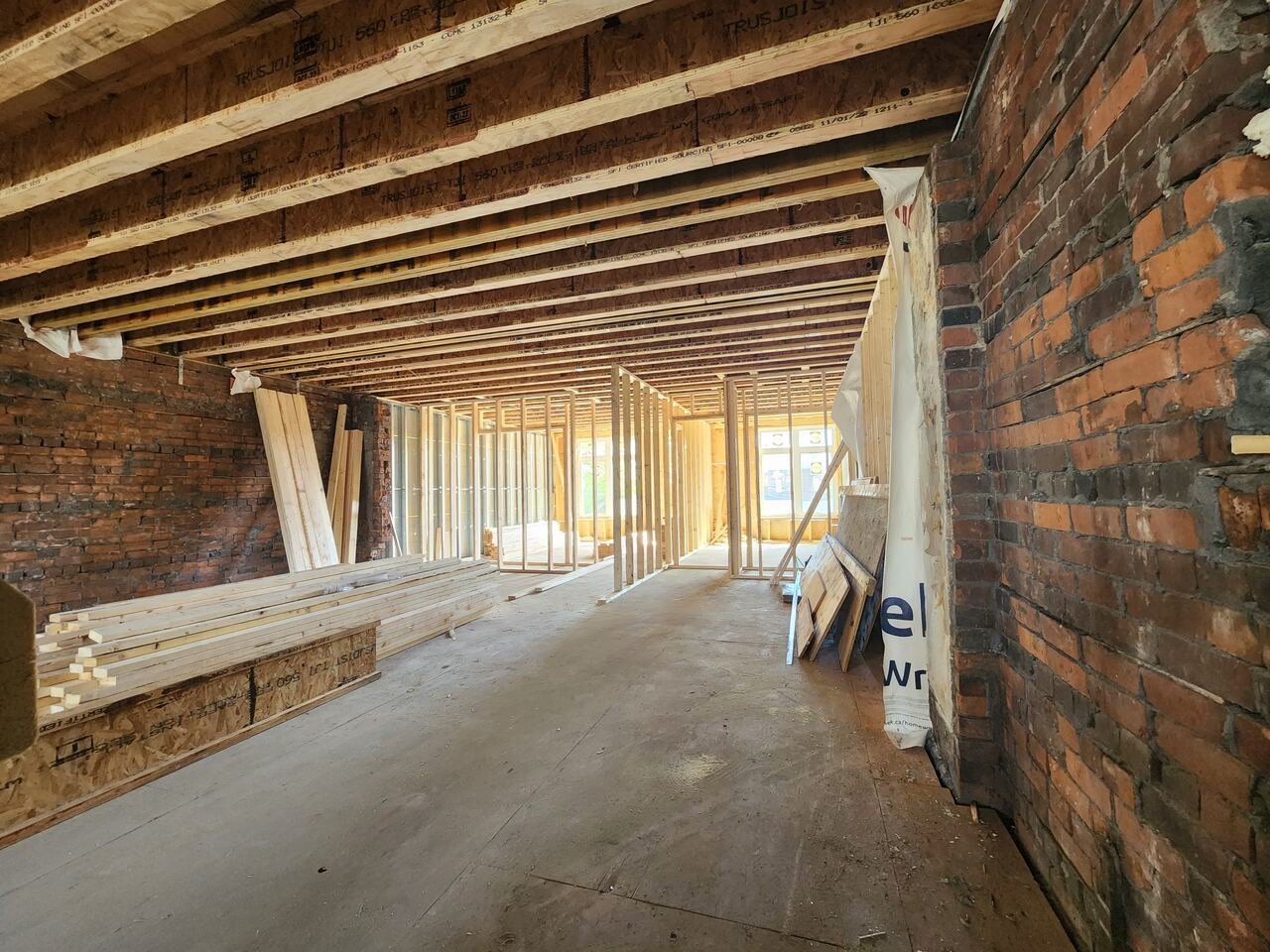 Interior at framing stage with engineered joists and original exposed brick party wall