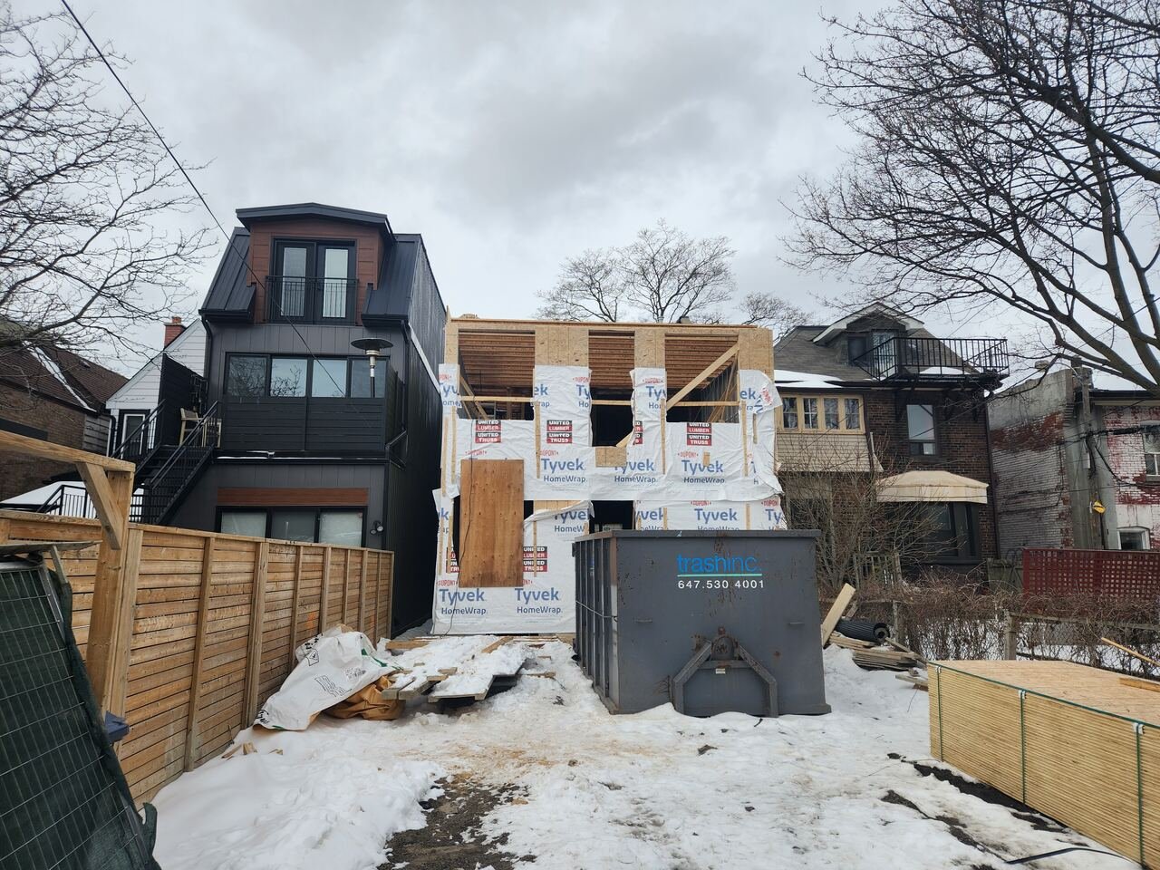 Rear addition framed and wrapped in winter beside the completed neighbouring build