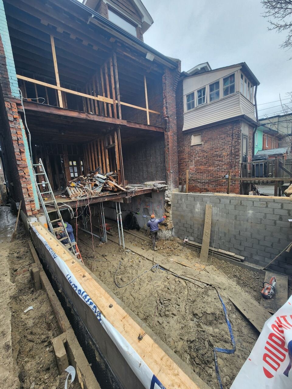Crew underpinning the foundation with shoring posts and new block wall