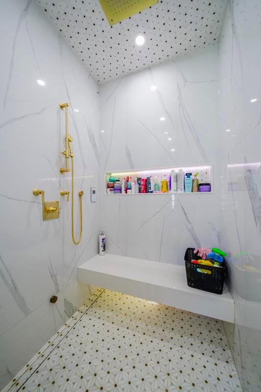 Walk-in marble shower with gold fixtures