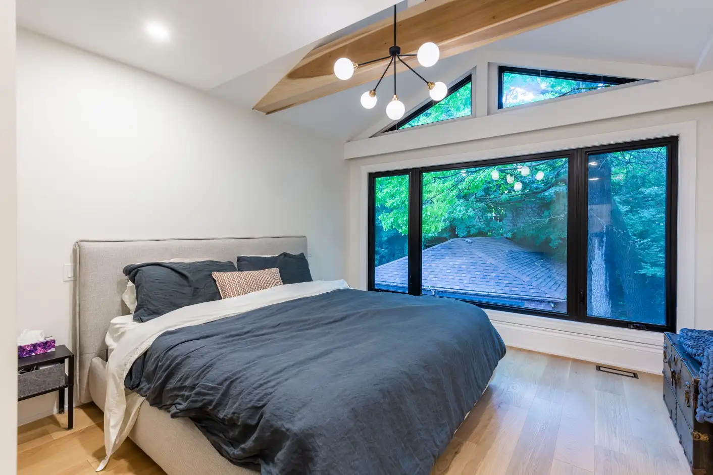 Primary bedroom with vaulted ceiling, wood beams and black-framed windows