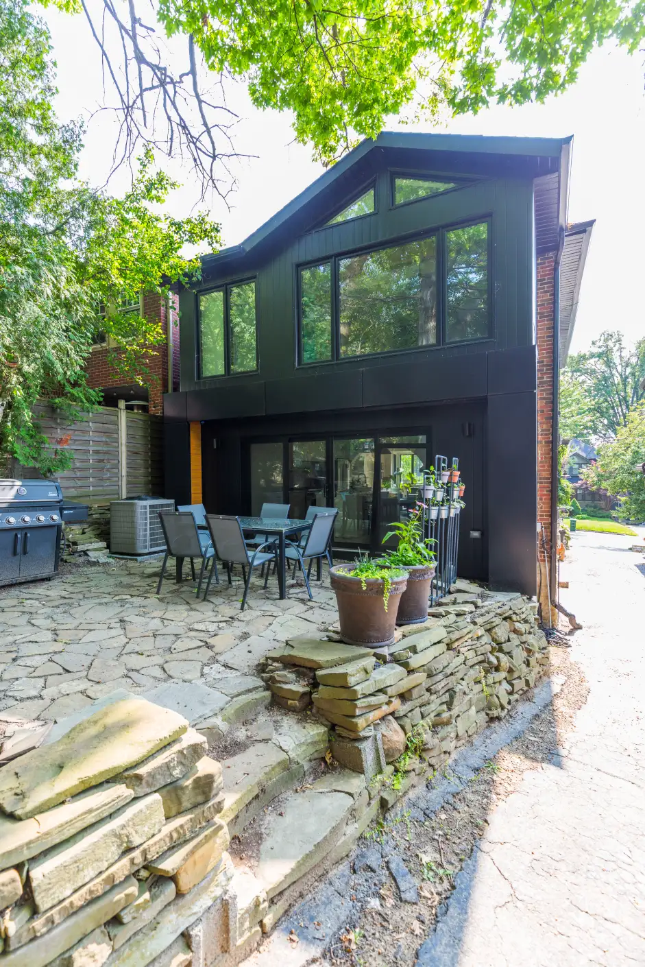 Rear exterior with black-clad two-storey addition and stone patio