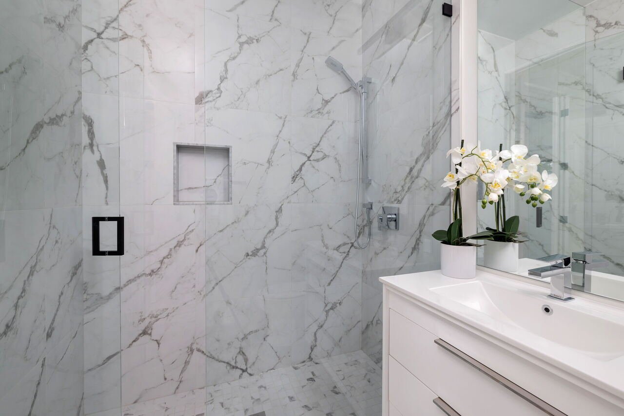 Bathroom with full-height marble tile, glass shower and niche