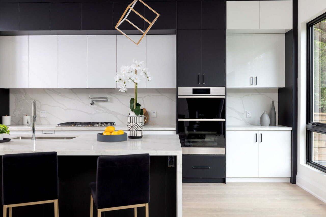 Modern kitchen with black and white cabinetry, quartz island and built-in double ovens