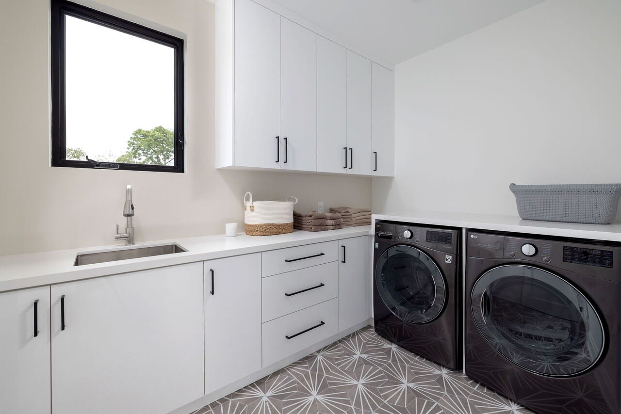 Laundry room with white cabinetry, quartz counter and patterned tile floor