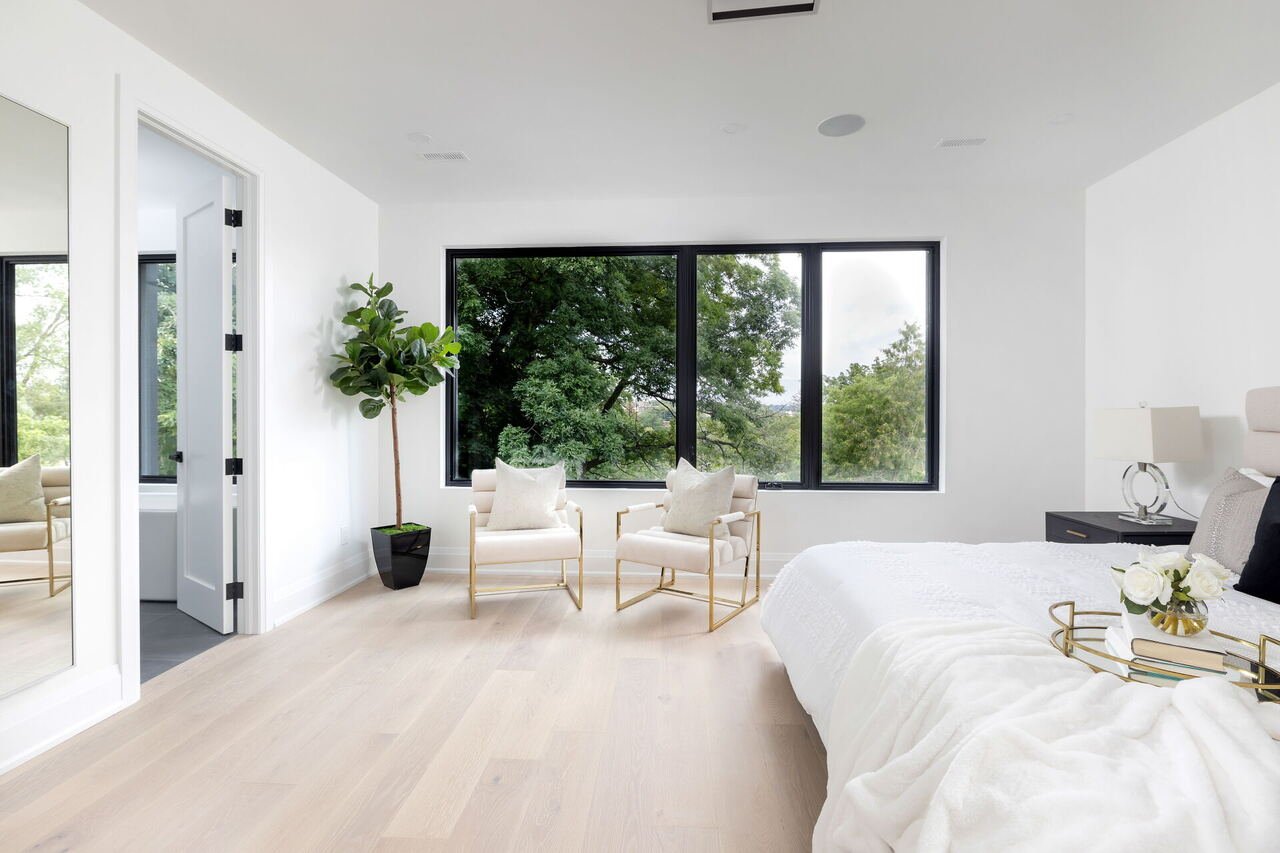 Primary bedroom with wide plank floors, picture windows and ensuite access
