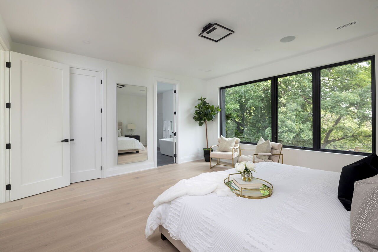 Primary bedroom with full-length mirror, double closets and treetop views
