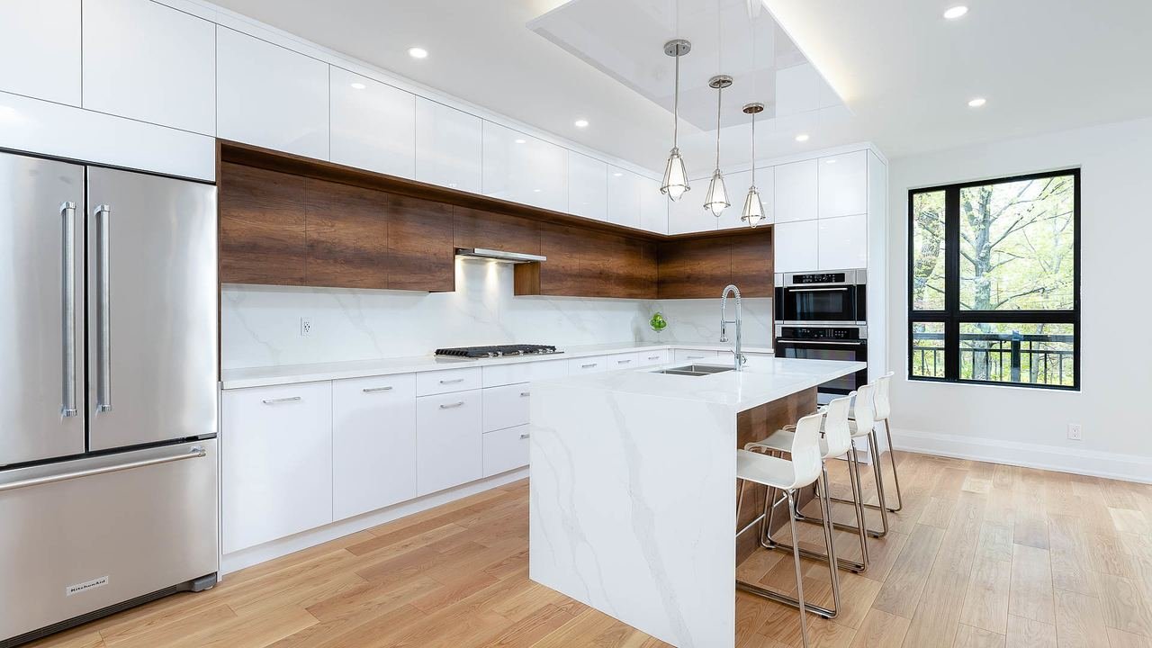 White kitchen with waterfall quartz island and wood accent panel