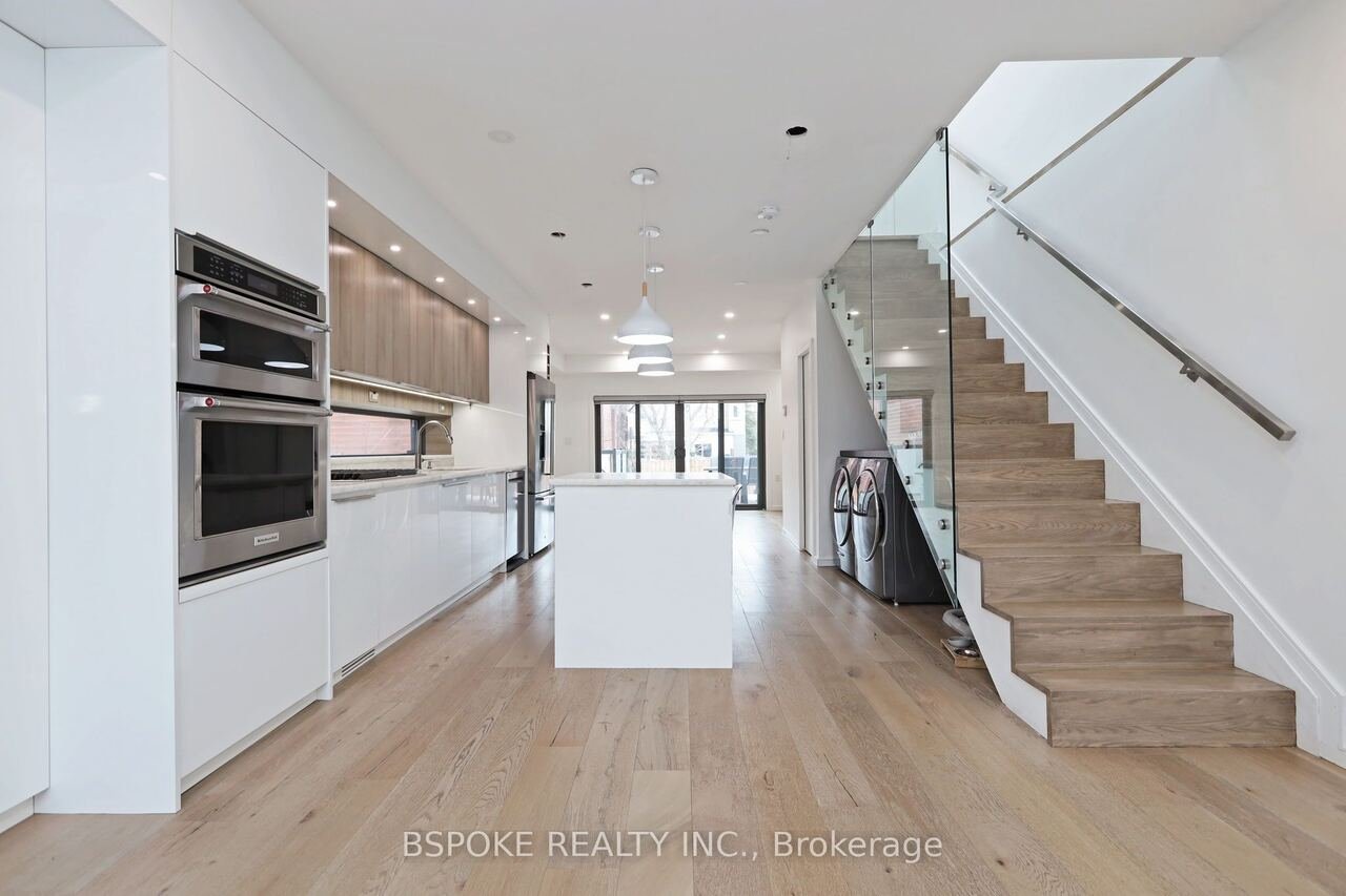 Kitchen and dining with glass-railed staircase and wide plank oak floors