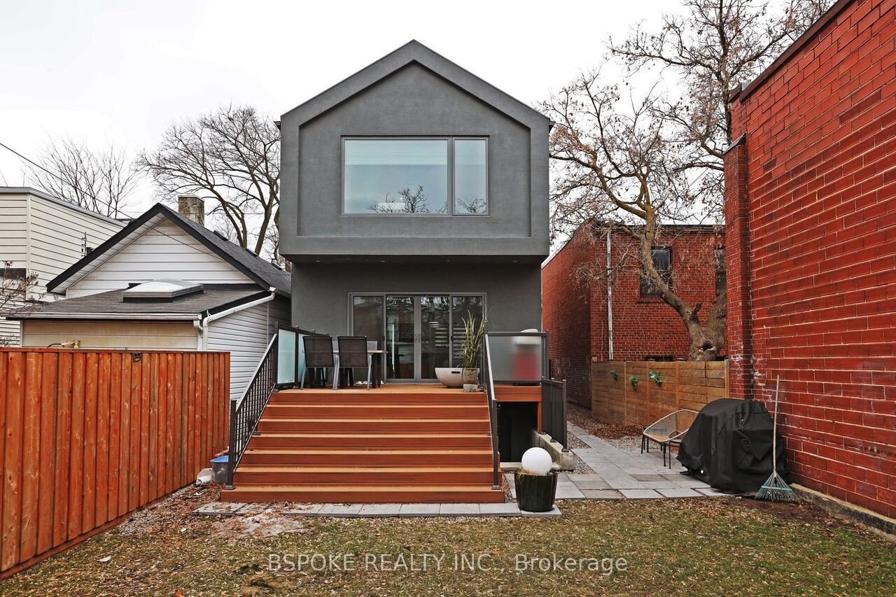 Rear exterior with cedar deck, patio and grey stucco addition