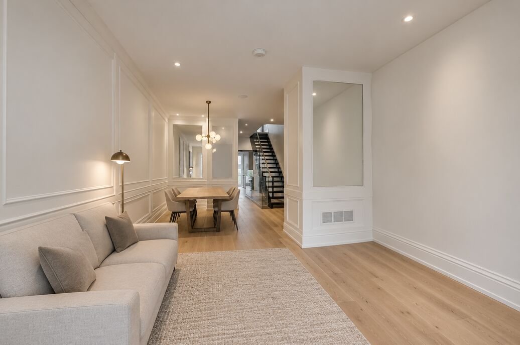 Living room opening through to the dining area and staircase, with wide-plank oak flooring and panelled walls
