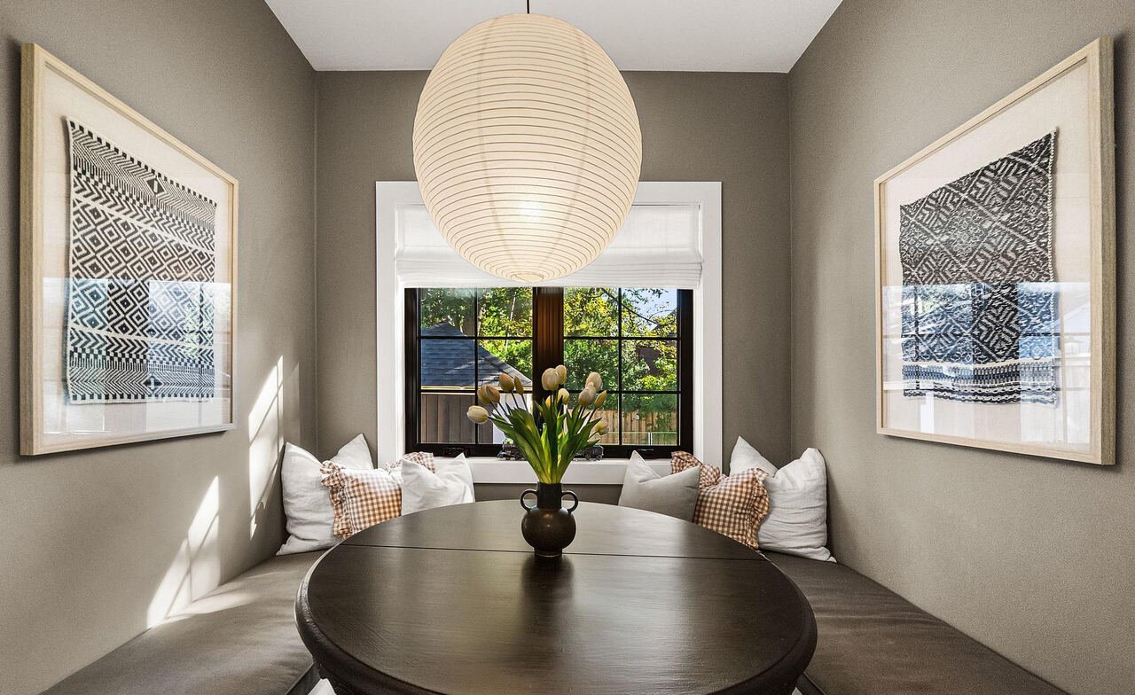 Built-in breakfast nook banquette with round table, framed textile art and garden view window