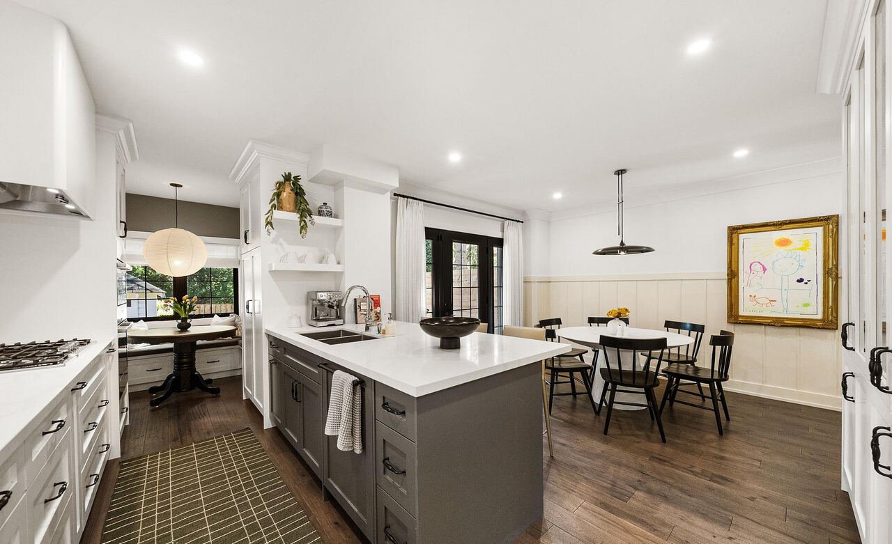 Grey kitchen island with quartz countertop, looking through to the built-in breakfast nook and dining area