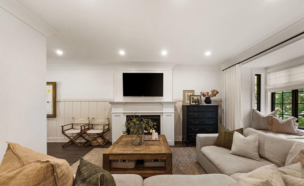 Living room with white fireplace surround, wall-mounted television and board and batten panelling
