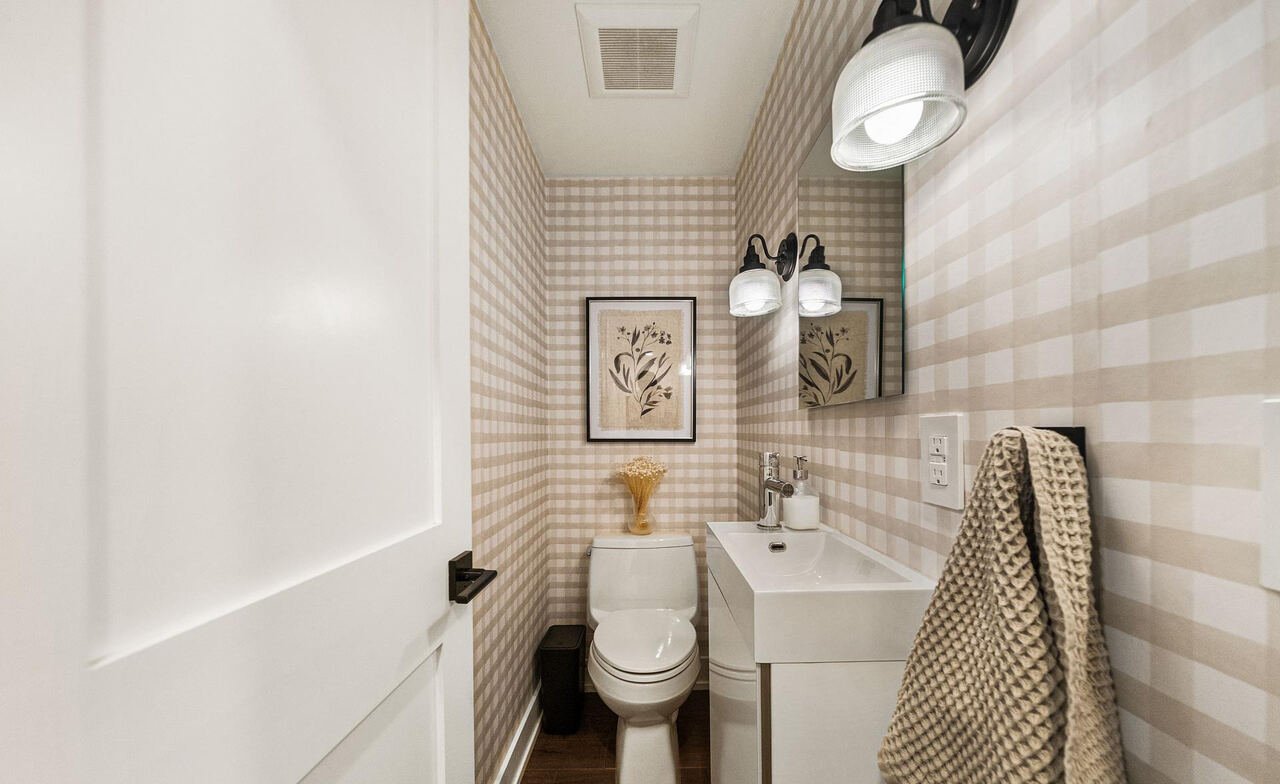 Main floor powder room with beige gingham wallpaper, wall-mount sink and black schoolhouse sconces