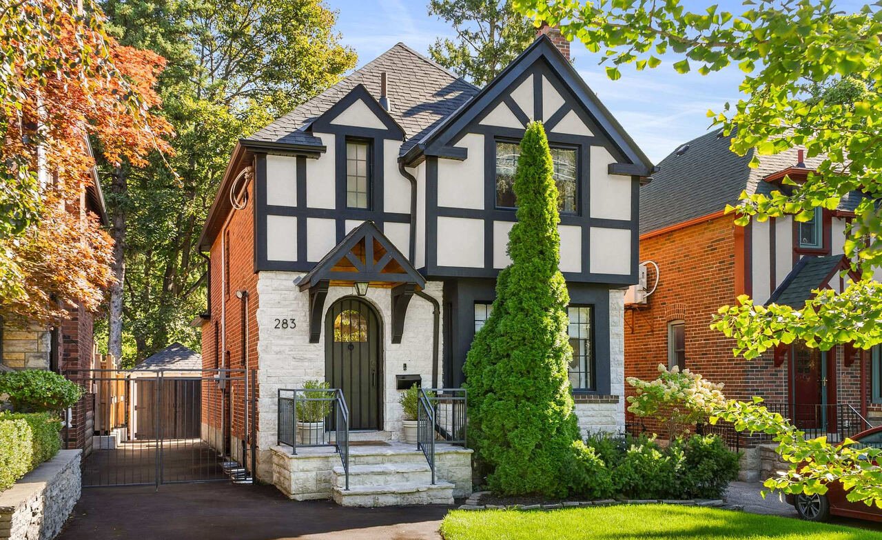 Restored Tudor home exterior with half-timbering, stone entry surround and arched front door at 283 South Kingsway, Toronto