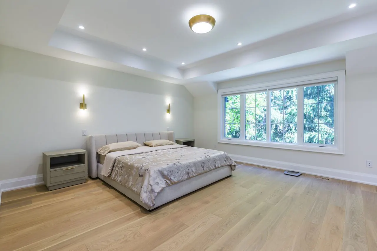 Primary bedroom with tray ceiling and wall sconces