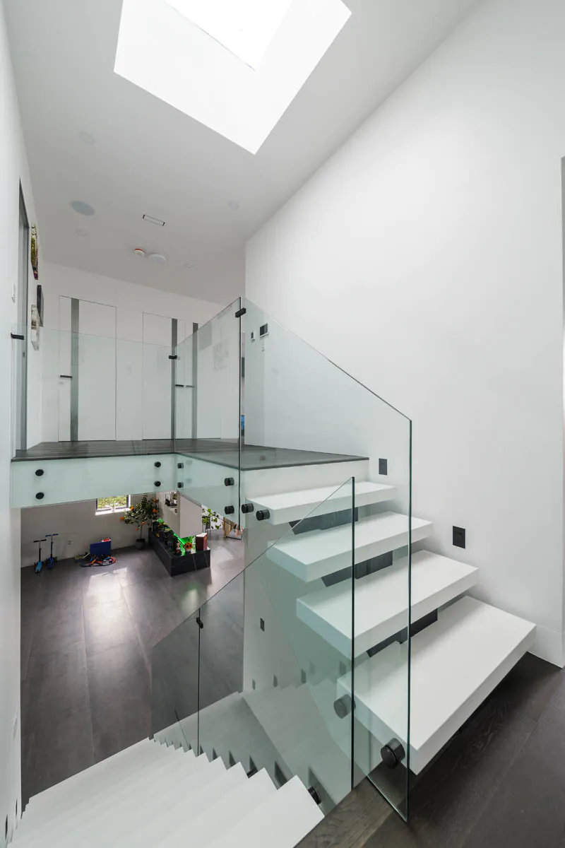 Staircase with glass railing and skylight above