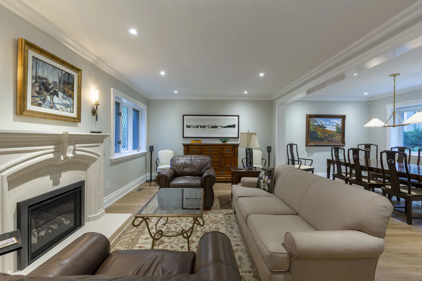 Renovated living room with limestone fireplace mantel and open flow to dining room