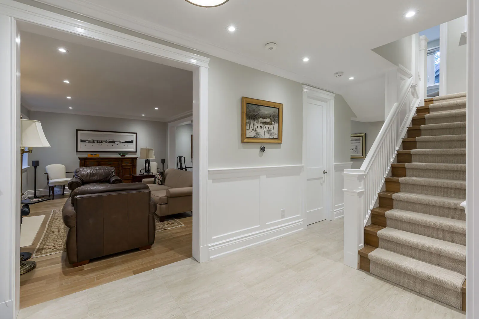 Renovated lower level hallway with wainscoting, travertine tile and carpeted staircase