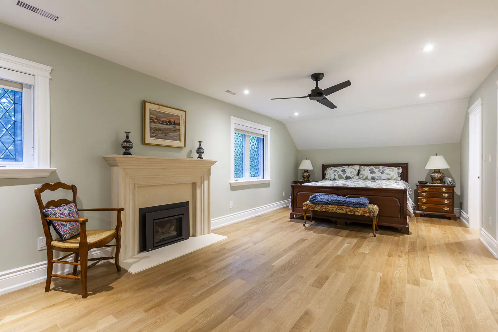 Renovated primary bedroom with limestone fireplace, leaded glass windows and white oak flooring