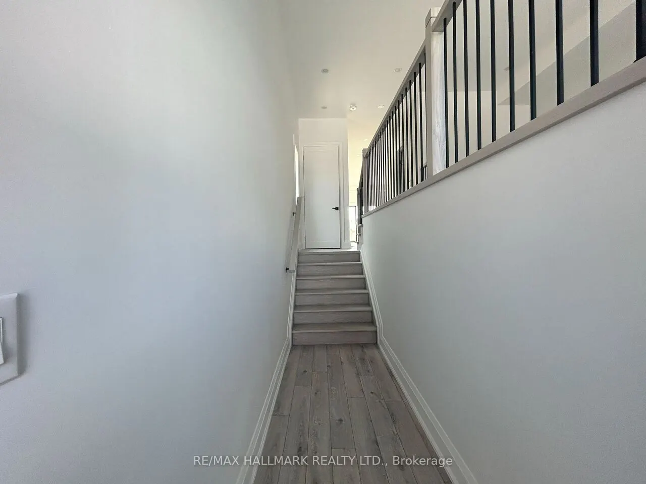Staircase hallway with light oak treads and black metal spindles